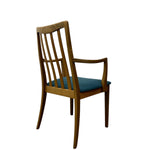Load image into Gallery viewer, A mid-century modern wooden dining chair with a slatted backrest, armrests, and a teal blue upholstered seat cushion, shown from a three-quarters angle on a white background.
