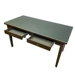 Load image into Gallery viewer, A mid-century modern writing desk with a dark green top and a bronze-brown wood frame, featuring two open drawers on the front.
