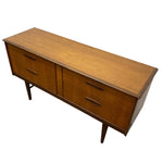 Load image into Gallery viewer, Mid-century modern wooden sideboard with a warm honey-toned wood grain finish, featuring four drawers with curved dark handles and tapered legs, shown on a plain white background.
