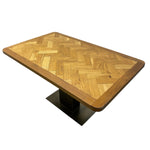 Load image into Gallery viewer, A rectangular wooden dining table with a herringbone parquet pattern top and a black metal pedestal base, shown on a plain white background.
