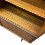 Load image into Gallery viewer, Close-up of a mid-century modern wooden cabinet or sideboard with a warm honey-toned wood grain finish and a dark wood drawer front.
