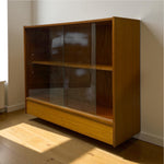 Load image into Gallery viewer, Wooden cabinet with glass doors in a room with sunlight casting shadows
