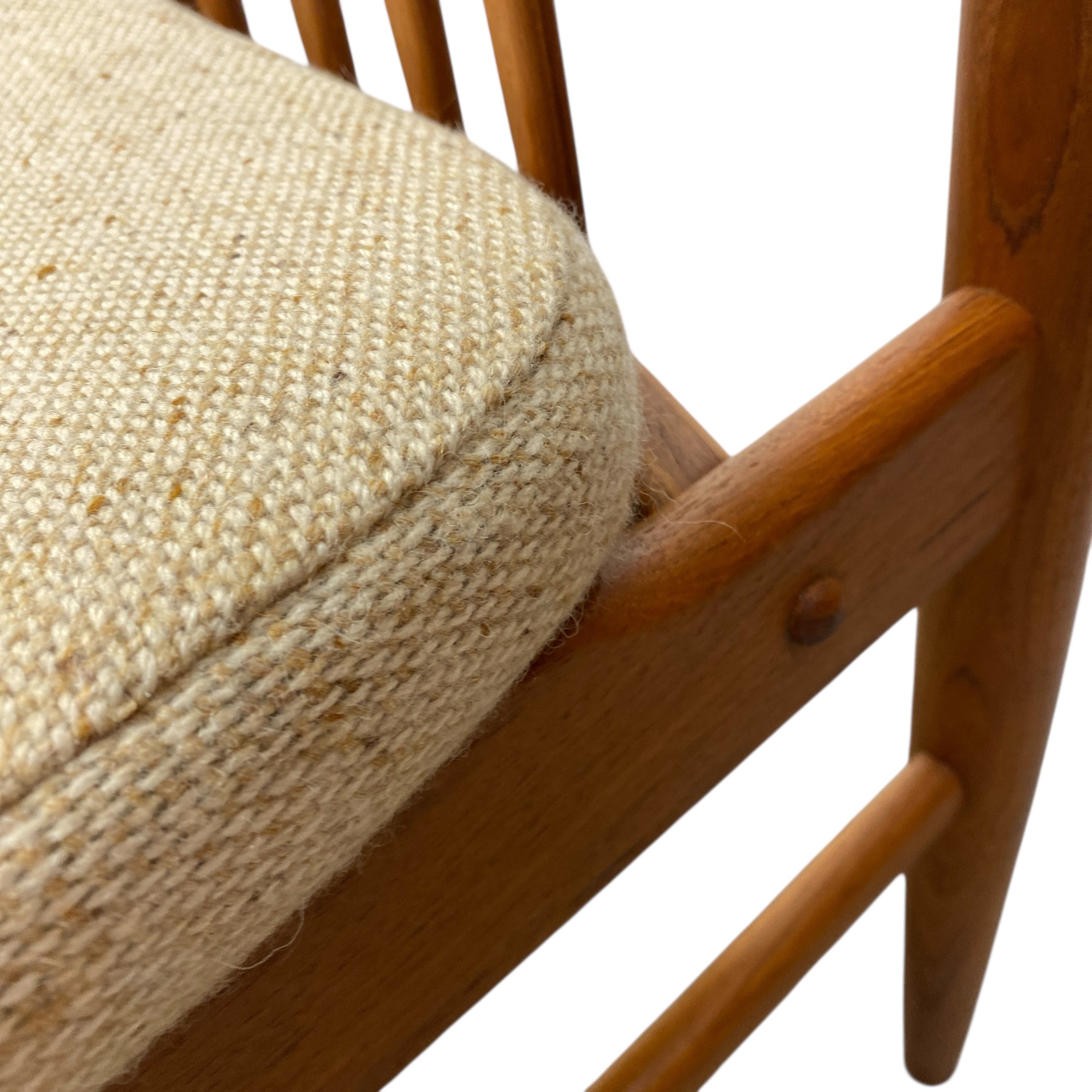 Close-up of a wooden chair with a beige cushion on a white background