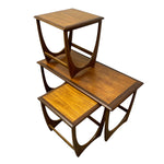 Load image into Gallery viewer, Three nested wooden nesting tables with a warm medium-brown finish and distinctive curved metal support legs, shown on a plain white background.
