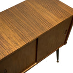 Load image into Gallery viewer, A close-up of a mid-century modern wooden sideboard cabinet with a rich walnut grain finish, featuring a top surface, two cabinet doors with narrow pull handles, and a single visible tapered metal leg against a white background.
