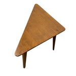 Load image into Gallery viewer, A triangular wooden side table with a warm medium-brown finish and tapered legs, shown from an elevated angle on a plain white background.
