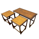 Load image into Gallery viewer, A mid-century modern nesting set of three wooden tables, including one rectangular coffee table and two smaller square side tables, made of warm medium-brown wood with dark brown curved metal legs.
