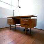 Load image into Gallery viewer, Wooden desk with drawers in a room with wooden flooring and a whiteboard.
