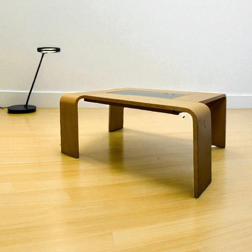Modern wooden coffee table in a minimalistic room with a lamp in the background.