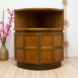 Wooden cabinet with curved top and two doors on a light wooden floor with decorative elements.