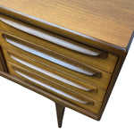 Load image into Gallery viewer, Close-up of a mid-century modern wooden sideboard or cabinet with three drawers featuring curved, recessed pulls and a tapered leg, shown against a plain white background.
