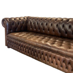 Load image into Gallery viewer, A brown leather Chesterfield sofa with deep button tufting, rolled arms, and nailhead trim, shown against a plain white background.
