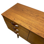 Load image into Gallery viewer, A mid-century modern wooden sideboard or credenza with a warm honey-brown wood grain finish, featuring three drawers with sculptural curved handles and a single visible leg, shown against a plain white background.
