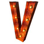 Load image into Gallery viewer, A large decorative letter V marquee light with a rusted orange and brown textured metal frame, illuminated by multiple warm yellow bulbs, shown on a plain white background.
