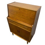 Load image into Gallery viewer, Mid-century modern wooden writing desk with a warm medium-brown wood grain finish, featuring a top drawer, two lower drawers with curved metal pulls, and two cabinet doors with dark handles.
