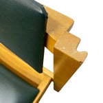 Load image into Gallery viewer, Close-up detail of a wooden chair or stool showing a light natural wood frame, a dark green upholstered backrest, and a matching green cushion, isolated on a white background.

