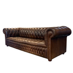 Load image into Gallery viewer, A classic Chesterfield-style leather sofa in a rich dark brown color, featuring deep button tufting, rolled arms, and nailhead trim, shown against a plain white background.
