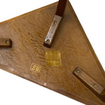 Load image into Gallery viewer, Close-up underside of a wooden table showing a triangular wood grain base, brass hardware, and a stamped 'B&amp;G' brand mark on a white background.
