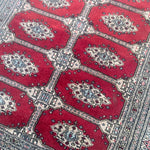 Load image into Gallery viewer, Close-up of a red patterned rug with geometric designs

