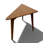 Load image into Gallery viewer, A triangular wooden side table with a warm medium-brown finish and tapered legs, shown on a white background with a prominent shadow.
