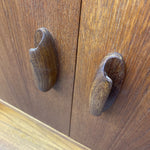 Load image into Gallery viewer, Two dark brown wooden cabinet handles with a unique curved, shell-like shape mounted on matching wood cabinet doors.

