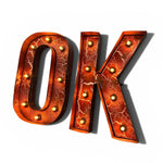 Load image into Gallery viewer, The letters 'O' and 'K' form the word 'OK' in a 3D retro marquee style, featuring a textured copper-orange metallic surface with white crackle details and gold light bulbs.
