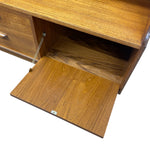 Load image into Gallery viewer, A close-up of a wooden storage cabinet or desk with a drawer partially open, showing the wood grain on the drawer front and interior shelf, isolated on a white background.
