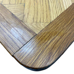 Load image into Gallery viewer, Close-up of a wooden table corner showing a glossy medium-brown wood grain finish and a lighter natural wood inlay pattern.

