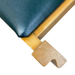 Load image into Gallery viewer, Close-up of a chair corner showing dark teal upholstered padding, a light natural wood frame, and a matching wooden support leg on a white background.
