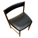 Load image into Gallery viewer, A mid-century modern dining chair with a black upholstered seat and curved backrest, supported by a light brown wooden frame, shown from an elevated angle on a white background.
