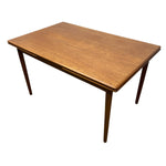 Load image into Gallery viewer, A mid-century modern wooden dining table with a warm medium-brown finish, featuring tapered legs and a drop-leaf design, shown against a plain white background.

