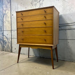 Load image into Gallery viewer, Wooden dresser with multiple drawers against a textured wall.
