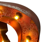 Load image into Gallery viewer, Close-up of a rusted metal decorative object with warm amber lighting glowing from integrated bulbs, showing a textured orange-brown surface with white crackle patterning against a white background.

