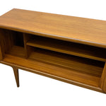 Load image into Gallery viewer, Mid-century modern wooden sideboard cabinet with a warm medium-brown wood grain finish, featuring an open shelf and a single tapered leg, shown against a plain white background.
