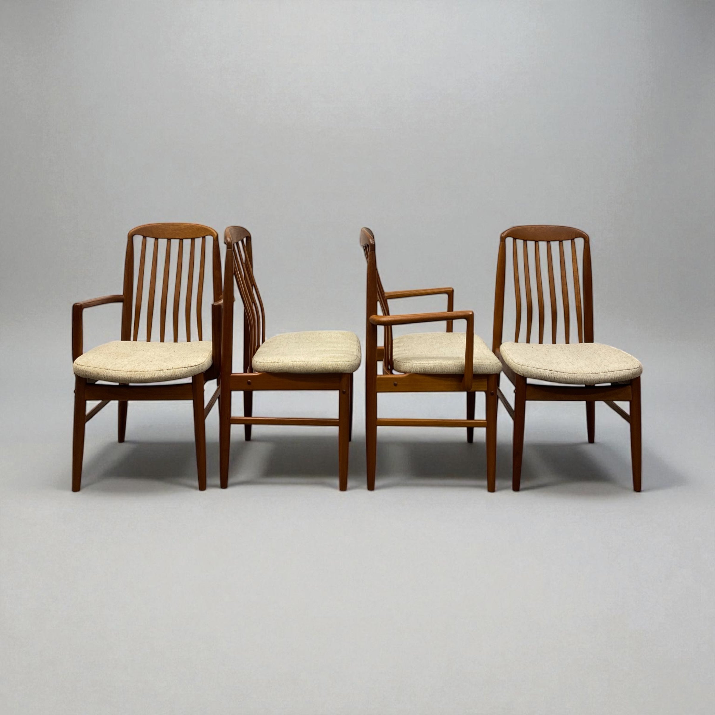 Four wooden chairs with white cushions on a gray background