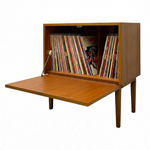 Load image into Gallery viewer, A mid-century modern wooden record cabinet with its lower shelf extended, filled with vinyl records, photographed against a solid white background.

