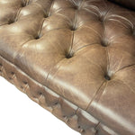 Load image into Gallery viewer, Close-up of a brown tufted leather sofa or chaise lounge seat, showing the buttoned upholstery and stitched edge against a white background.
