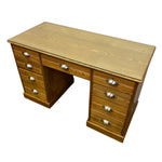 Load image into Gallery viewer, A mid-century modern wooden writing desk with a glass top, featuring a warm oak finish, multiple drawers on both sides, and polished silver metal handles, shown on a plain white background.
