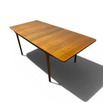 Load image into Gallery viewer, A mid-century modern rectangular wooden dining table with tapered legs, shown from an elevated angle on a white background with a soft shadow.
