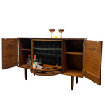 Load image into Gallery viewer, Mid-century modern wooden bar cabinet with open doors, glass wine bottle storage, open shelves, and a pull-out bar tray holding bottles and glasses, shown on a white background.

