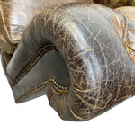 Load image into Gallery viewer, Close-up of a distressed dark brown leather armrest with prominent crackled texture and brass nailhead trim on a white background.
