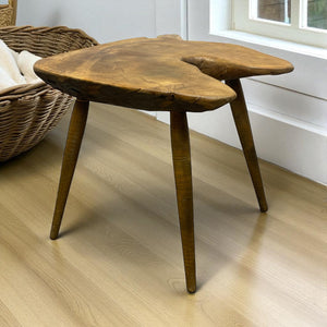Wooden side table with a unique design on a light wooden floor.