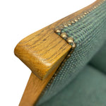 Load image into Gallery viewer, Close-up of a wooden chair armrest with green fabric and brass studs on a white background
