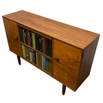Load image into Gallery viewer, Mid-century modern wooden sideboard cabinet with a warm walnut finish, featuring two glass-front bookshelves filled with books and a right-side cabinet door with a small wooden pull handle, shown on a plain white background.
