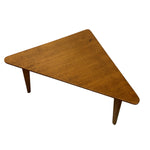 Load image into Gallery viewer, A triangular wooden coffee table with a warm medium-brown finish and tapered legs, shown from an elevated angle on a plain white background.
