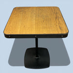 Load image into Gallery viewer, Wooden table with black base on a light blue background
