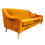 Load image into Gallery viewer, A mid-century modern three-seater sofa upholstered in mustard yellow velvet, featuring a tufted backrest, rolled arms, tapered wooden legs, and two matching throw pillows, shown against a plain white background.
