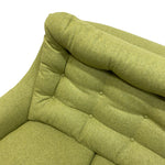 Load image into Gallery viewer, Close-up of a tufted armchair upholstered in textured olive green fabric, showing the backrest, button tufting, and rolled armrest against a plain white background.
