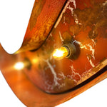 Load image into Gallery viewer, Close-up of a rustic copper-toned metal light fixture with a glowing warm bulb, showing a textured, distressed finish with white marbling details against a white background.
