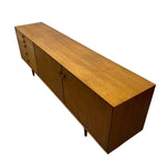 Load image into Gallery viewer, Mid-century modern wooden sideboard cabinet with a warm medium-brown wood grain finish, featuring four drawers on the left and two doors on the right, shown on a plain white background.
